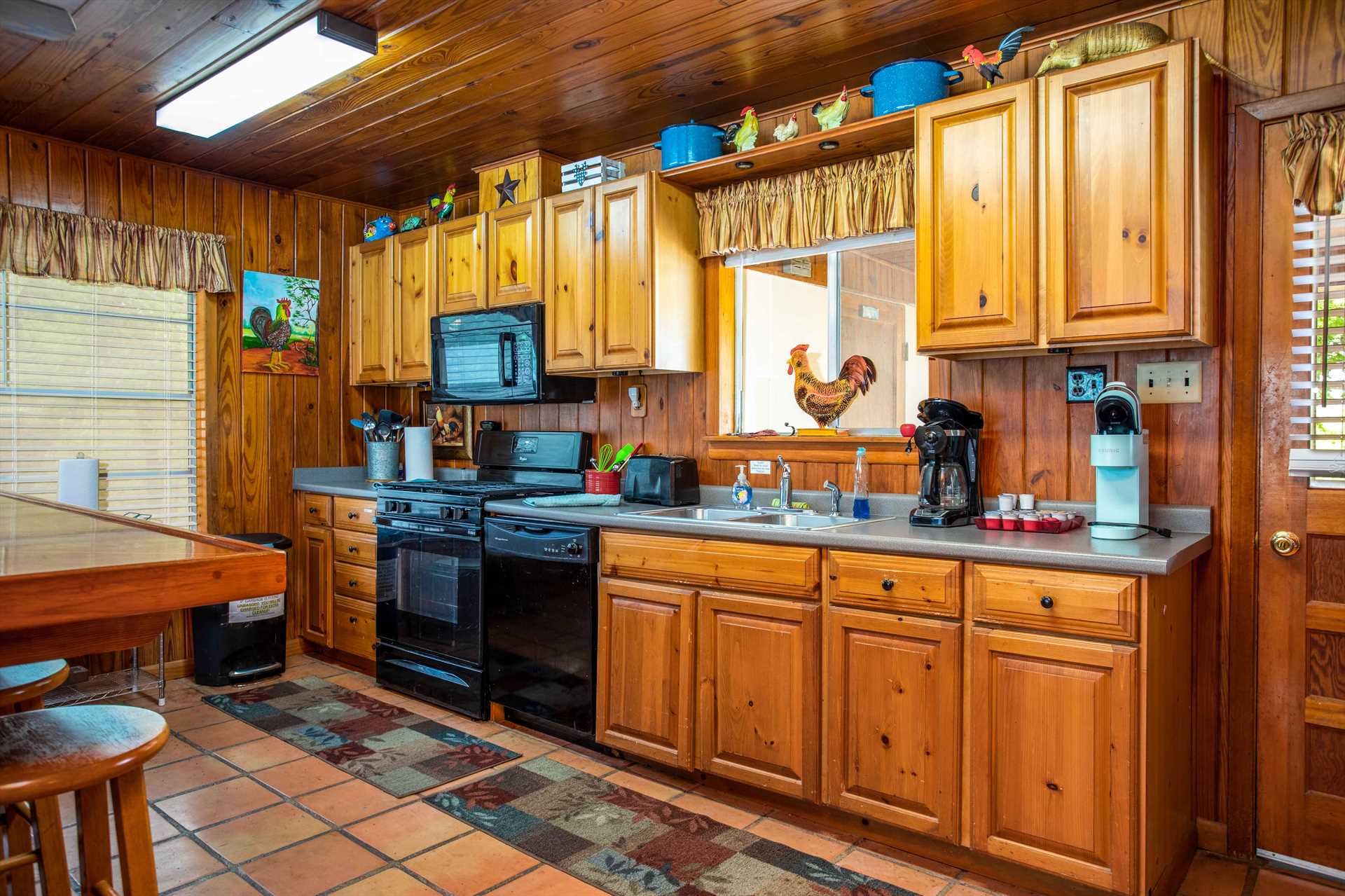                                                 A golden glow surrounds the full country kitchen, equipped with appliances, cooking ware, and serving ware.