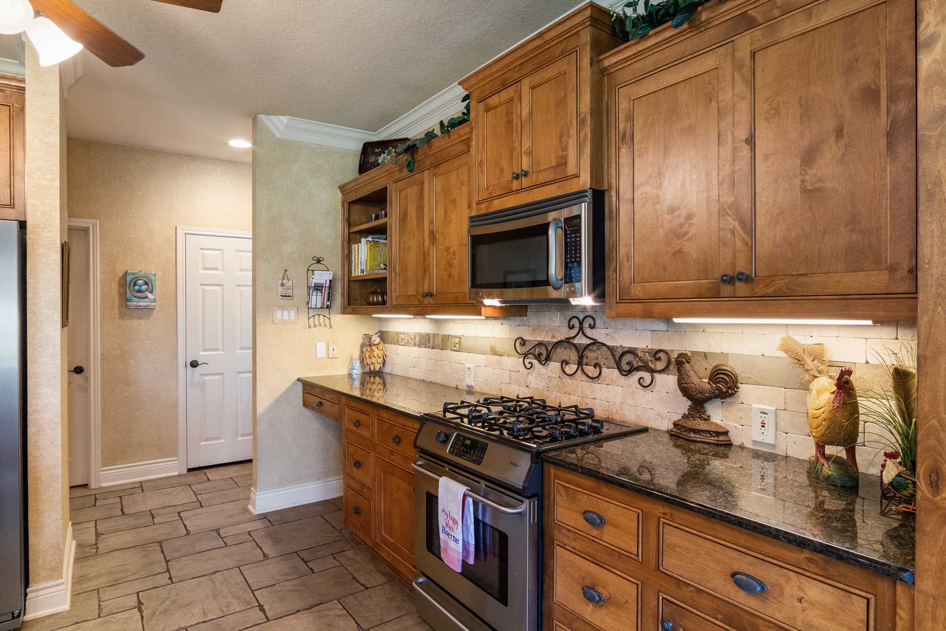                                                 The pretty wood cabinetry in the kitchen opens up to plenty of cooking ware, dining ware, utensils, and glasses.
