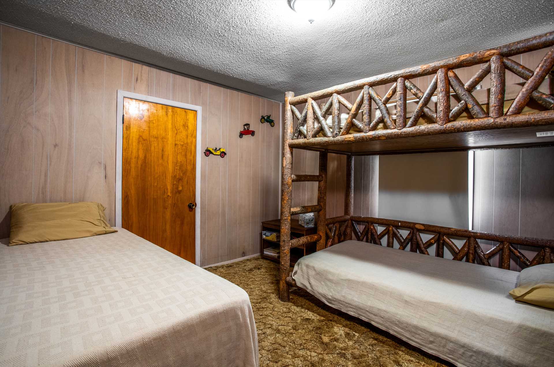                                                 The fifth bedroom features three single beds, two of them stacked in a sturdy and rustic bunk style.