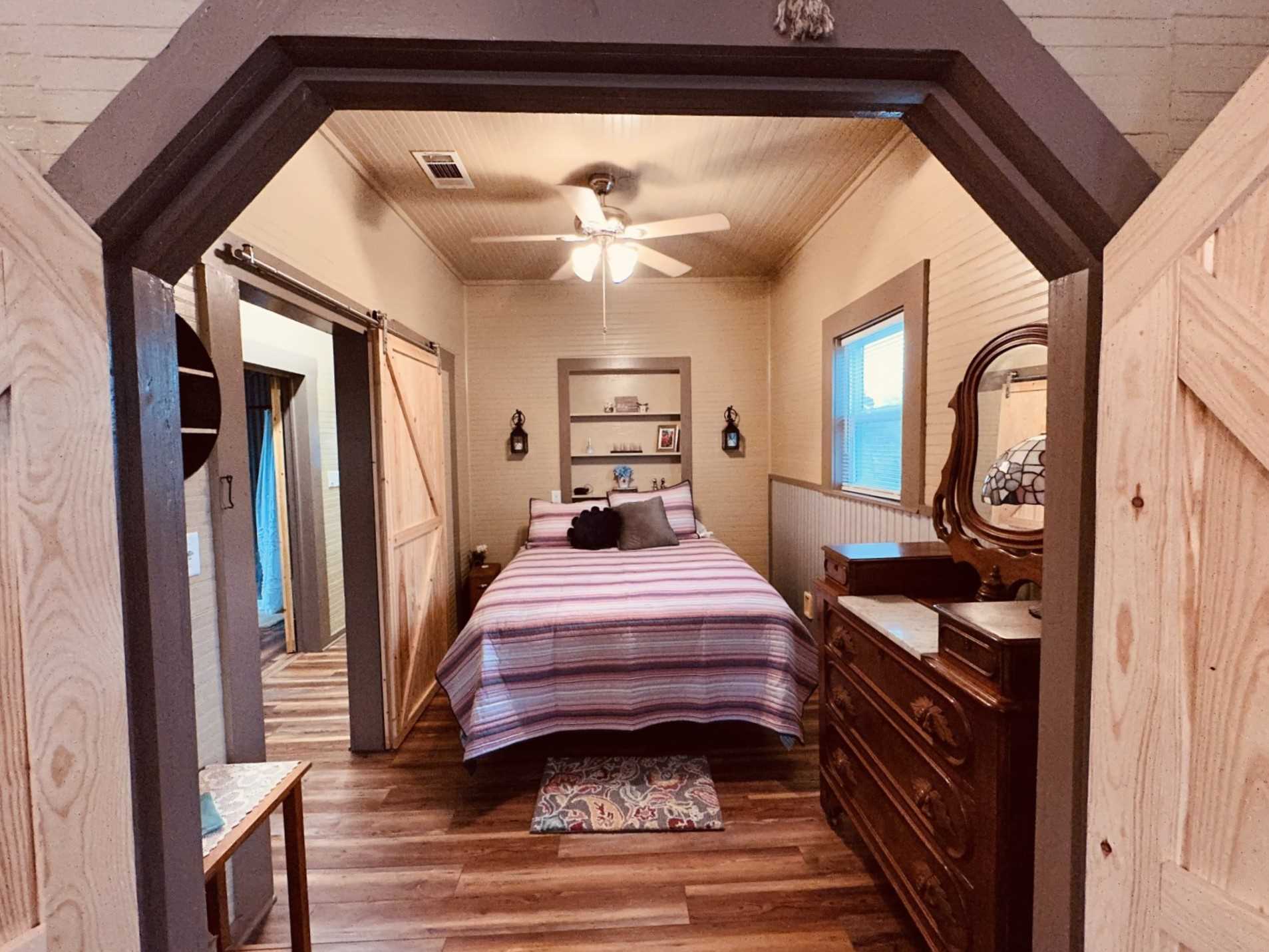                                                 The bedroom at the Texas Blue Apple Cottage features a plush queen-sized bed, storage, and cozy country comfort!