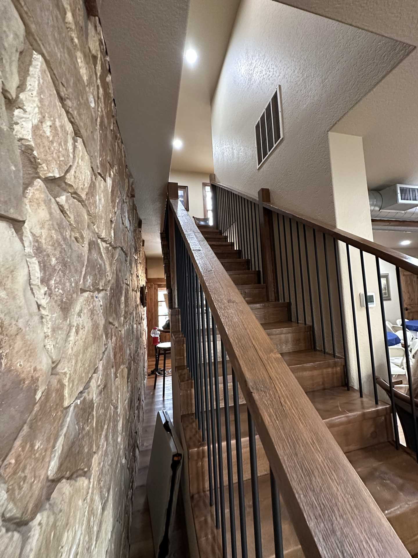                                                 The den, kitchen, and master bedroom suite are downstairs, with four bedrooms and baths upstairs. This view of the staircase also shows the wonderful harmonizing of stone and wood work details in the Lodge!